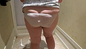 Skrytá kamera zachytí zrelú bacuľatú milfku pri skúšaní šortiek v kabínke.