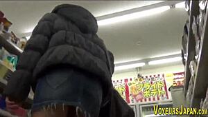 Aasialainen tyttö sukkahousuissa seuraillaan salaa julkisella ulkoalueella