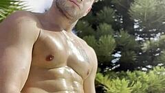 Bold oily masturbation in public outdoor setting.