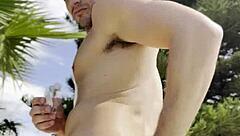 Bold oily masturbation in public outdoor setting.