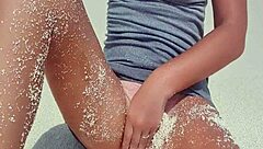 Blonde relaxes by the sea, showing off her curves in the sand