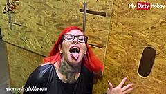 Busty redhead jerks hard cocks in gloryhole.