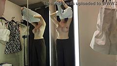 A blonde tries on see-through clothes in the mall changing room