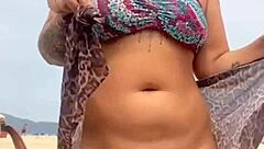 Young African woman strips naked on beach, guy gets hard, she grabs his erect penis