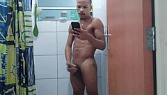 acordei com tesão e gozei durante o banho, sentindo o pau grande pulsar forte no chuveiro.