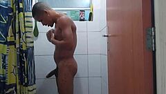 acordei com tesão e gozei durante o banho, sentindo o pau grande pulsar forte no chuveiro.