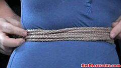 The bound and waxed submissive endures a close-up whipping session from the dominant male, highlighting her tattooed nipples in this intense fetish encounter