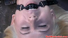 The bound and waxed submissive endures a close-up whipping session from the dominant male, highlighting her tattooed nipples in this intense fetish encounter