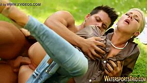 Clothed woman drenches outdoors in golden shower scene