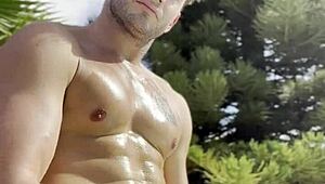 Bold oily masturbation in public outdoor setting.