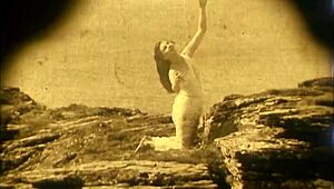 Nude woman poses by waterfall in 1920 vintage scene