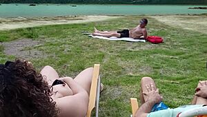 Човек, пипам се на плажа, докато воайор си бие наблизо.