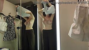 A blonde tries on see-through clothes in the mall changing room