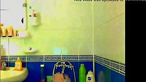 Tattooed model plays with glass dildo in bathroom