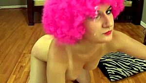 girl in bright pink afro wig bent over in messy pose.